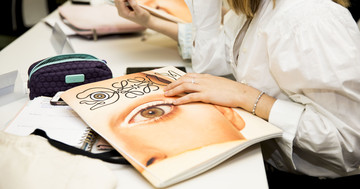 Carpeta Loewe Una carpeta de la marca Loewe sobre un pupitre y una mano sobre ella