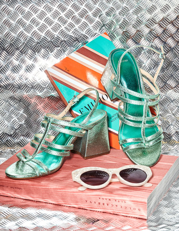 Estilismo de moda junior Bodegón en colores pastel y fondo metálico con sandalias de tacón, un libro y otros elementos