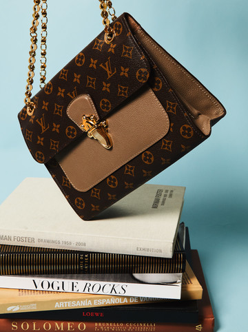 Periodismo de moda Un bolso de Louis Vuitton suspendido encima de libros sobre moda