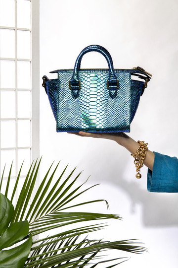 Estilismo de moda Un bolso sostenido por una mano y elementos vegetales en la parte inferior